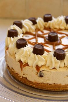 a no - bake caramel rolo cheesecake on a glass cake plate