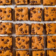 chocolate chip cookie bars are lined up on a sheet of parchment paper, ready to be eaten