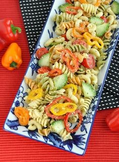 pasta salad with peppers and cucumbers in a blue and white plate on a red tablecloth