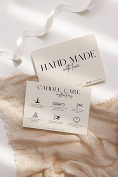 two business cards sitting on top of a white sheet covered in fabric and satin ribbon