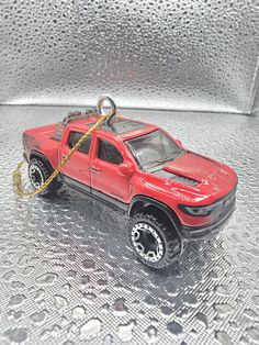 a red toy truck with a chain attached to it's front end on a shiny surface