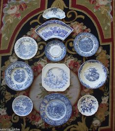 blue and white plates are arranged on a rug