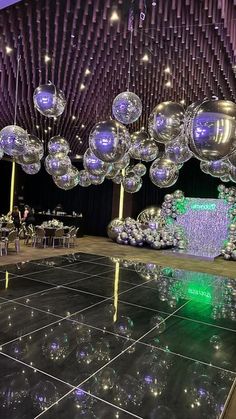 a dance floor with many shiny balls hanging from the ceiling and tables set up in front of it