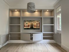 an empty living room with built - in shelving units and a painting on the wall