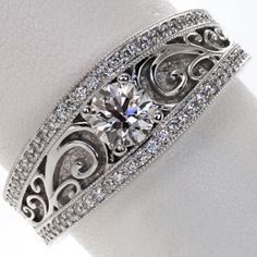 a white gold ring with an intricate design and round brilliant diamonds on the band is shown