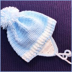 a blue and white knitted hat on top of a purple blanket