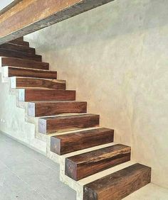 a set of wooden stairs leading up to a second story room with white walls and concrete flooring