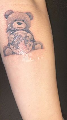 a small teddy bear tattoo on the right arm and leg, it appears to be in plastic wrap