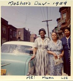 two women standing next to each other in front of an old car on the street