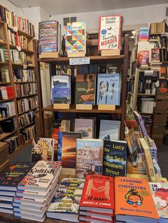 many books are on display in a book store with shelves full of books behind them