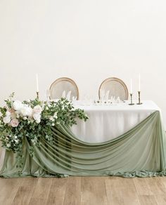 the table is set with white flowers and greenery