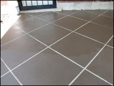 a brown tile floor with white lines on it and a black door in the background