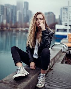 a woman is sitting on the edge of a dock with her hand to her mouth