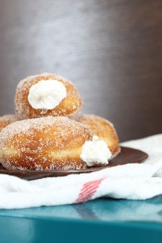 three sugar covered donuts sitting on top of a brown plate next to a white towel