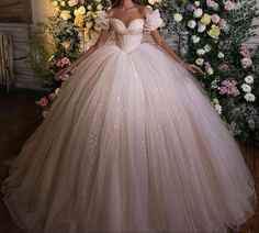 a woman in a ball gown standing next to flowers