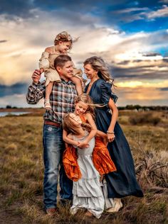 a family is posing for a photo in the middle of an open field at sunset