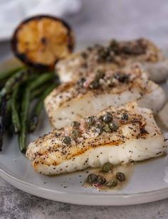 a white plate topped with fish and asparagus