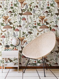 a wicker chair sitting in front of a wall with mushrooms and plants on it