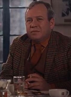 a man sitting at a table with cups and saucers