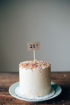 a white cake with sprinkles and a sign on top