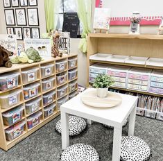 a room filled with lots of books and toy bins next to a table full of stuffed animals