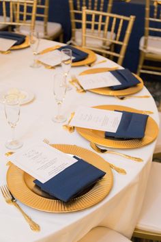 the table is set with gold and blue place settings, silverware, and napkins