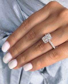 a woman's hand with a diamond ring on her finger and a white manicured nail