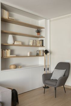 a living room filled with furniture and bookshelves next to a wall mounted book shelf