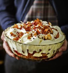 a person holding a glass dish with food in it and toppings on the top