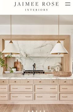 a kitchen with white marble counter tops and wooden cabinets, along with hanging lights over the island