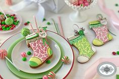 decorated cookies and candy are on plates at a holiday table with pink, green and white decorations