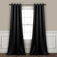 black curtains hanging on the wall in front of a window with white trim and wood flooring