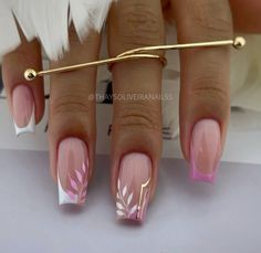 a woman's hand with pink and white nail designs on her nails, holding a gold bar