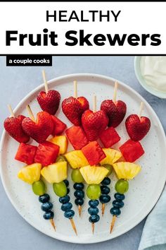 fruit skewers on a white plate with blueberries, strawberries and pineapples