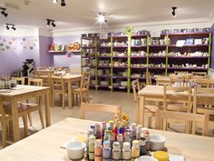 an empty restaurant with wooden tables and chairs in front of shelves filled with paint supplies