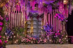 a decorated stage with purple flowers and greenery