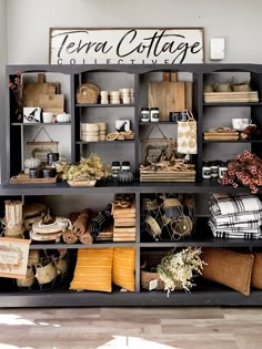 a shelf filled with lots of different items on top of a hard wood floor next to a sign that says terra cottage