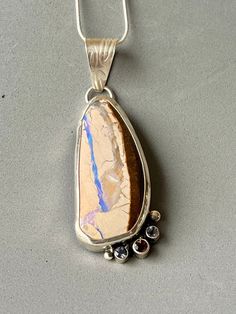 "Large Australian Boulder Opal with streaks of lavender and dark brown with in the light sand colored stone. A 4mm smokey quartz and two 3.5mm iolite complement this beautifully. The opal measures approximately 50 x 20mm. Overall the piece measures approximately 3 x 7 /8\", including the hand textured bail. All set in sterling silver. The chain is 24\", or you can add your own." Smoky Quartz Gemstone Jewelry, Brown Smoky Quartz Gemstone Jewelry, Brown Smoky Quartz Jewelry With Natural Stones, Elegant Brown Jewelry With Large Stone, Brown Pendant Jewelry With Natural Inclusions, Artisan Brown Jewelry With Natural Inclusions, White Topaz Earrings, Green Tourmaline Ring, Australian Boulder Opal