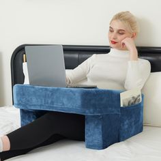 a woman sitting on a bed using a laptop