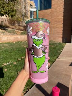 a person holding up a pink cup with the grin on it