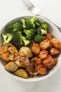 a bowl filled with potatoes and broccoli on top of a white tablecloth