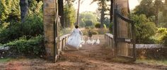 a man walking down a dirt road next to a gate