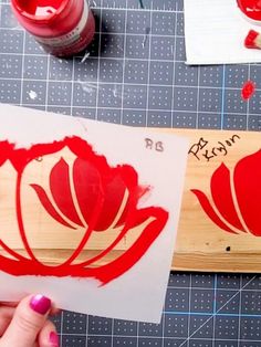 a person is painting red flowers on wood with acrylic paint and watercolors