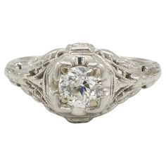 an antique style diamond ring with filigrees on the band and center stone