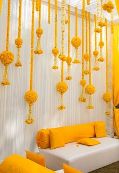 a white couch sitting under a yellow drape covered wall with lots of hanging decorations