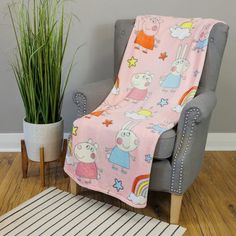 a chair with a pink blanket on it next to a potted plant and rug