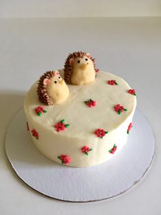 two hedgehogs sitting on top of a frosted cake