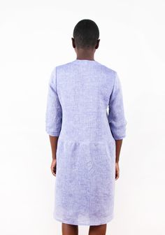 the back view of a woman wearing a purple linen shirt dress with pockets and buttons