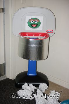 a trash can with a face on it and some toilet paper in front of it