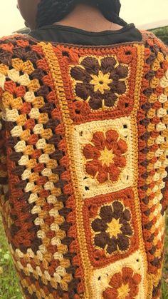 the back of a woman's sweater with crocheted flowers and leaves on it